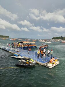 Tourists enjoy jet skiing and boat rides at a busy coastal dock on a sunny day.