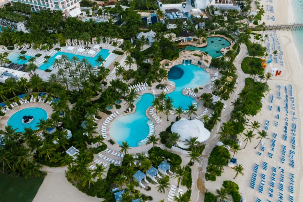 pexels-photo-9400917-9400917 A stunning aerial view of a luxurious beachfront resort with swimming pools and palm trees.